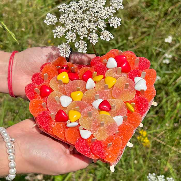 Gateau de bonbons en forme de coeur dans les tons de rouge jaune et blanc contenant des bonbons à la peche et au chocolat au lait